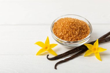 Aromatik vanilya şekeri. Vanilya kabukları. Vanilya çubukları, esmer ve beyaz şeker dokulu arka planda bir kasede. Vanilya çiçekleri, baharatlar ve tatlı ve pişirme için bitkiler. Mesaj için yer var. Boşluğu kopyala
