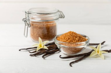 Aromatik vanilya şekeri. Vanilya kabukları. Vanilya çubukları, esmer ve beyaz şeker dokulu arka planda bir kasede. Vanilya çiçekleri, baharatlar ve tatlı ve pişirme için bitkiler. Mesaj için yer var. Boşluğu kopyala