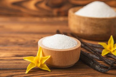 Aromatik vanilya şekeri. Vanilya kabukları. Vanilya çubukları, esmer ve beyaz şeker dokulu arka planda bir kasede. Vanilya çiçekleri, baharatlar ve tatlı ve pişirme için bitkiler. Mesaj için yer var. Boşluğu kopyala