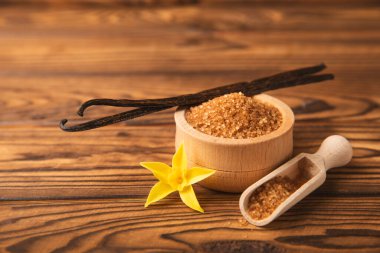 Aromatik vanilya şekeri. Vanilya kabukları. Vanilya çubukları, esmer ve beyaz şeker dokulu arka planda bir kasede. Vanilya çiçekleri, baharatlar ve tatlı ve pişirme için bitkiler. Mesaj için yer var. Boşluğu kopyala