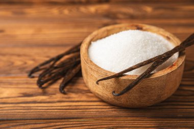 Aromatik vanilya şekeri. Vanilya kabukları. Vanilya çubukları, esmer ve beyaz şeker dokulu arka planda bir kasede. Vanilya çiçekleri, baharatlar ve tatlı ve pişirme için bitkiler. Mesaj için yer var. Boşluğu kopyala