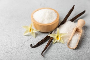 Aromatik vanilya şekeri. Vanilya kabukları. Vanilya çubukları, esmer ve beyaz şeker dokulu arka planda bir kasede. Vanilya çiçekleri, baharatlar ve tatlı ve pişirme için bitkiler. Mesaj için yer var. Boşluğu kopyala