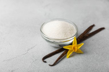 Aromatik vanilya şekeri. Vanilya kabukları. Vanilya çubukları, esmer ve beyaz şeker dokulu arka planda bir kasede. Vanilya çiçekleri, baharatlar ve tatlı ve pişirme için bitkiler. Mesaj için yer var. Boşluğu kopyala