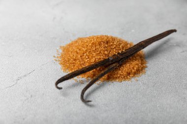 Aromatik vanilya şekeri. Vanilya kabukları. Vanilya çubukları, esmer ve beyaz şeker dokulu arka planda bir kasede. Vanilya çiçekleri, baharatlar ve tatlı ve pişirme için bitkiler. Mesaj için yer var. Boşluğu kopyala