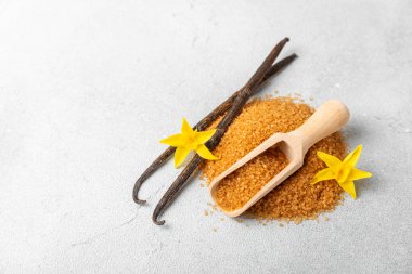 Aromatik vanilya şekeri. Vanilya kabukları. Vanilya çubukları, esmer ve beyaz şeker dokulu arka planda bir kasede. Vanilya çiçekleri, baharatlar ve tatlı ve pişirme için bitkiler. Mesaj için yer var. Boşluğu kopyala