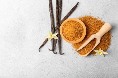 Aromatik vanilya şekeri. Vanilya kabukları. Vanilya çubukları, esmer ve beyaz şeker dokulu arka planda bir kasede. Vanilya çiçekleri, baharatlar ve tatlı ve pişirme için bitkiler. Mesaj için yer var. Boşluğu kopyala