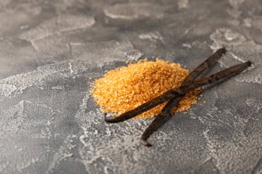 Aromatik vanilya şekeri. Vanilya kabukları. Vanilya çubukları, esmer ve beyaz şeker dokulu arka planda bir kasede. Vanilya çiçekleri, baharatlar ve tatlı ve pişirme için bitkiler. Mesaj için yer var. Boşluğu kopyala