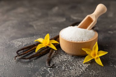 Aromatik vanilya şekeri. Vanilya kabukları. Vanilya çubukları, esmer ve beyaz şeker dokulu arka planda bir kasede. Vanilya çiçekleri, baharatlar ve tatlı ve pişirme için bitkiler. Mesaj için yer var. Boşluğu kopyala