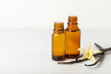 Bir şişe vanilya yağı ve desenli arka planda vanilya çiçeği. aromatik vanilyalı fasulye. Vanilya özü. Spa konsepti. Güzellik ve özen. Mesaj için yer. Boşluğu kopyala.