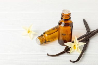 Bir şişe vanilya yağı ve desenli arka planda vanilya çiçeği. aromatik vanilyalı fasulye. Vanilya özü. Spa konsepti. Güzellik ve özen. Mesaj için yer. Boşluğu kopyala.