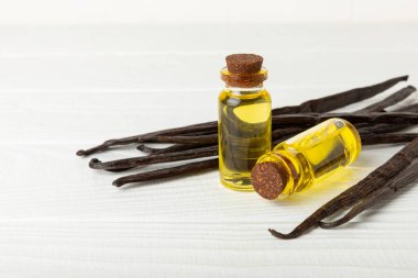 Bir şişe vanilya yağı ve desenli arka planda vanilya çiçeği. aromatik vanilyalı fasulye. Vanilya özü. Spa konsepti. Güzellik ve özen. Mesaj için yer. Boşluğu kopyala.