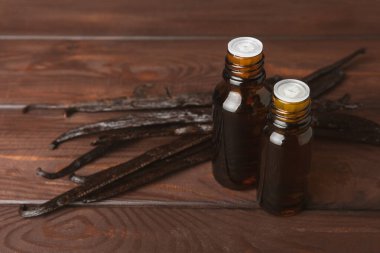 Bir şişe vanilya yağı ve desenli arka planda vanilya çiçeği. aromatik vanilyalı fasulye. Vanilya özü. Spa konsepti. Güzellik ve özen. Mesaj için yer. Boşluğu kopyala.