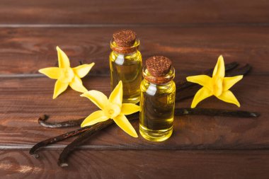 Bir şişe vanilya yağı ve desenli arka planda vanilya çiçeği. aromatik vanilyalı fasulye. Vanilya özü. Spa konsepti. Güzellik ve özen. Mesaj için yer. Boşluğu kopyala.