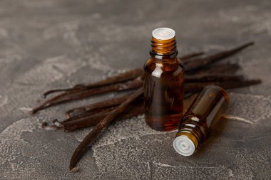 Bir şişe vanilya yağı ve desenli arka planda vanilya çiçeği. aromatik vanilyalı fasulye. Vanilya özü. Spa konsepti. Güzellik ve özen. Mesaj için yer. Boşluğu kopyala.