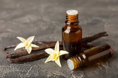 Bir şişe vanilya yağı ve desenli arka planda vanilya çiçeği. aromatik vanilyalı fasulye. Vanilya özü. Spa konsepti. Güzellik ve özen. Mesaj için yer. Boşluğu kopyala.