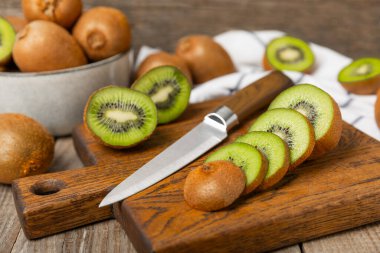 Ahşap arka planda Kivi. Masada tam meyve ve dilimler halinde yeşil kivi var. Taze sulu kivi. Tropik meyve. Organik meyve. Sağlıklı beslenme. Mesaj için yer var. Boşluğu kopyala