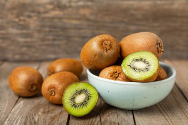 Ahşap arka planda Kivi. Masada tam meyve ve dilimler halinde yeşil kivi var. Taze sulu kivi. Tropik meyve. Organik meyve. Sağlıklı beslenme. Mesaj için yer var. Boşluğu kopyala