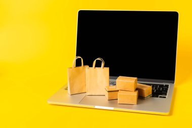 Çevrimiçi alışveriş kavramı. Karton kutu ve parlak renkli bir arka planda tramvayda alışveriş poşetleri. Alışveriş sepeti. İnternetten bilgisayar, tablet, telefon ve kredi kartı kullanarak alışveriş. Eve teslim.