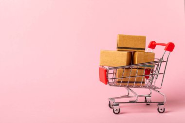 Çevrimiçi alışveriş kavramı. Karton kutu ve parlak renkli bir arka planda tramvayda alışveriş poşetleri. Alışveriş sepeti. İnternetten bilgisayar, tablet, telefon ve kredi kartı kullanarak alışveriş. Eve teslim.