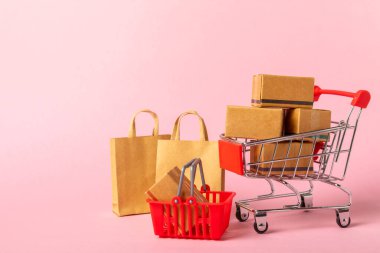 Çevrimiçi alışveriş kavramı. Karton kutu ve parlak renkli bir arka planda tramvayda alışveriş poşetleri. Alışveriş sepeti. İnternetten bilgisayar, tablet, telefon ve kredi kartı kullanarak alışveriş. Eve teslim.