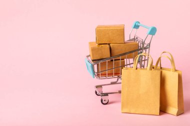 Çevrimiçi alışveriş kavramı. Karton kutu ve parlak renkli bir arka planda tramvayda alışveriş poşetleri. Alışveriş sepeti. İnternetten bilgisayar, tablet, telefon ve kredi kartı kullanarak alışveriş. Eve teslim.