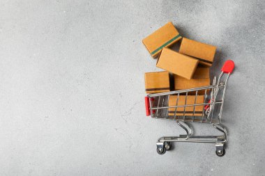 Çevrimiçi alışveriş kavramı. Karton kutu ve parlak renkli bir arka planda tramvayda alışveriş poşetleri. Alışveriş sepeti. İnternetten bilgisayar, tablet, telefon ve kredi kartı kullanarak alışveriş. Eve teslim.