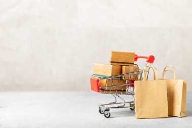 Çevrimiçi alışveriş kavramı. Karton kutu ve parlak renkli bir arka planda tramvayda alışveriş poşetleri. Alışveriş sepeti. İnternetten bilgisayar, tablet, telefon ve kredi kartı kullanarak alışveriş. Eve teslim.