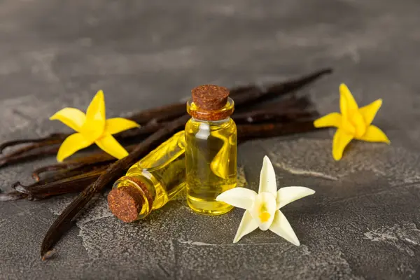 Bir şişe vanilya yağı ve desenli arka planda vanilya çiçeği. aromatik vanilyalı fasulye. Vanilya özü. Spa konsepti. Güzellik ve özen. Mesaj için yer. Boşluğu kopyala.