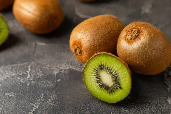 Ahşap arka planda Kivi. Masada tam meyve ve dilimler halinde yeşil kivi var. Taze sulu kivi. Tropik meyve. Organik meyve. Sağlıklı beslenme. Mesaj için yer var. Boşluğu kopyala