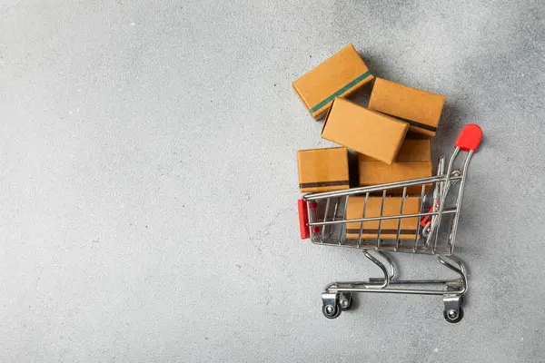 Çevrimiçi alışveriş kavramı. Karton kutu ve parlak renkli bir arka planda tramvayda alışveriş poşetleri. Alışveriş sepeti. İnternetten bilgisayar, tablet, telefon ve kredi kartı kullanarak alışveriş. Eve teslim.