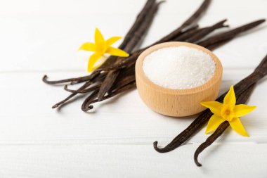 Aromatik vanilya şekeri. Vanilya kabukları. Vanilya çubukları, esmer ve beyaz şeker dokulu arka planda bir kasede. Vanilya çiçekleri, baharatlar ve tatlı ve pişirme için bitkiler. Mesaj için yer var. Boşluğu kopyala