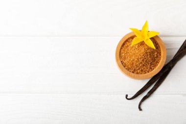 Aromatik vanilya şekeri. Vanilya kabukları. Vanilya çubukları, esmer ve beyaz şeker dokulu arka planda bir kasede. Vanilya çiçekleri, baharatlar ve tatlı ve pişirme için bitkiler. Mesaj için yer var. Boşluğu kopyala