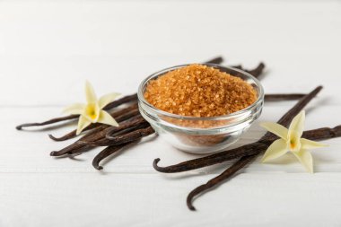 Aromatik vanilya şekeri. Vanilya kabukları. Vanilya çubukları, esmer ve beyaz şeker dokulu arka planda bir kasede. Vanilya çiçekleri, baharatlar ve tatlı ve pişirme için bitkiler. Mesaj için yer var. Boşluğu kopyala