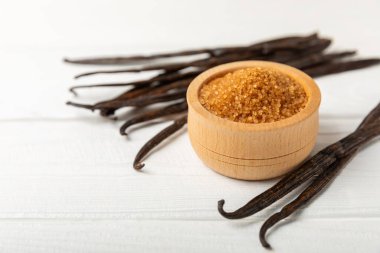 Aromatik vanilya şekeri. Vanilya kabukları. Vanilya çubukları, esmer ve beyaz şeker dokulu arka planda bir kasede. Vanilya çiçekleri, baharatlar ve tatlı ve pişirme için bitkiler. Mesaj için yer var. Boşluğu kopyala