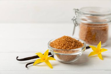 Aromatik vanilya şekeri. Vanilya kabukları. Vanilya çubukları, esmer ve beyaz şeker dokulu arka planda bir kasede. Vanilya çiçekleri, baharatlar ve tatlı ve pişirme için bitkiler. Mesaj için yer var. Boşluğu kopyala