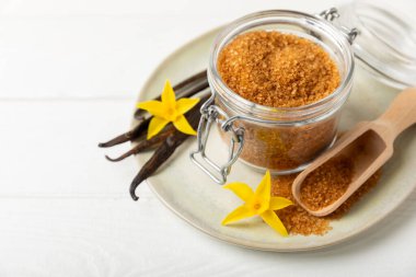 Aromatik vanilya şekeri. Vanilya kabukları. Vanilya çubukları, esmer ve beyaz şeker dokulu arka planda bir kasede. Vanilya çiçekleri, baharatlar ve tatlı ve pişirme için bitkiler. Mesaj için yer var. Boşluğu kopyala