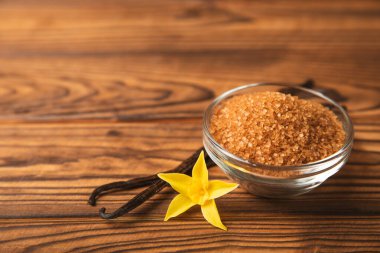 Aromatik vanilya şekeri. Vanilya kabukları. Vanilya çubukları, esmer ve beyaz şeker dokulu arka planda bir kasede. Vanilya çiçekleri, baharatlar ve tatlı ve pişirme için bitkiler. Mesaj için yer var. Boşluğu kopyala