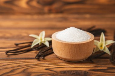 Aromatik vanilya şekeri. Vanilya kabukları. Vanilya çubukları, esmer ve beyaz şeker dokulu arka planda bir kasede. Vanilya çiçekleri, baharatlar ve tatlı ve pişirme için bitkiler. Mesaj için yer var. Boşluğu kopyala