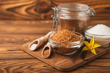 Aromatik vanilya şekeri. Vanilya kabukları. Vanilya çubukları, esmer ve beyaz şeker dokulu arka planda bir kasede. Vanilya çiçekleri, baharatlar ve tatlı ve pişirme için bitkiler. Mesaj için yer var. Boşluğu kopyala