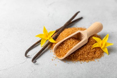 Aromatik vanilya şekeri. Vanilya kabukları. Vanilya çubukları, esmer ve beyaz şeker dokulu arka planda bir kasede. Vanilya çiçekleri, baharatlar ve tatlı ve pişirme için bitkiler. Mesaj için yer var. Boşluğu kopyala