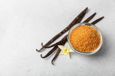 Aromatik vanilya şekeri. Vanilya kabukları. Vanilya çubukları, esmer ve beyaz şeker dokulu arka planda bir kasede. Vanilya çiçekleri, baharatlar ve tatlı ve pişirme için bitkiler. Mesaj için yer var. Boşluğu kopyala