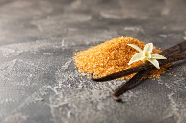 Aromatik vanilya şekeri. Vanilya kabukları. Vanilya çubukları, esmer ve beyaz şeker dokulu arka planda bir kasede. Vanilya çiçekleri, baharatlar ve tatlı ve pişirme için bitkiler. Mesaj için yer var. Boşluğu kopyala