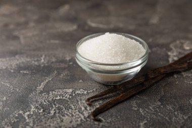 Aromatik vanilya şekeri. Vanilya kabukları. Vanilya çubukları, esmer ve beyaz şeker dokulu arka planda bir kasede. Vanilya çiçekleri, baharatlar ve tatlı ve pişirme için bitkiler. Mesaj için yer var. Boşluğu kopyala