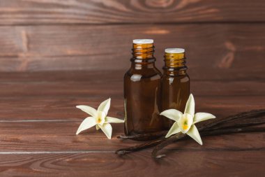 Bir şişe vanilya yağı ve desenli arka planda vanilya çiçeği. aromatik vanilyalı fasulye. Vanilya özü. Spa konsepti. Güzellik ve özen. Mesaj için yer. Boşluğu kopyala.