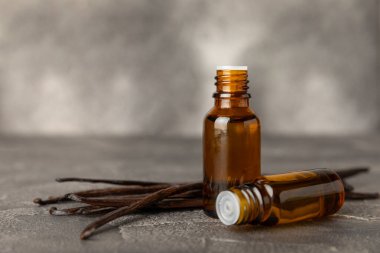 Bir şişe vanilya yağı ve desenli arka planda vanilya çiçeği. aromatik vanilyalı fasulye. Vanilya özü. Spa konsepti. Güzellik ve özen. Mesaj için yer. Boşluğu kopyala.