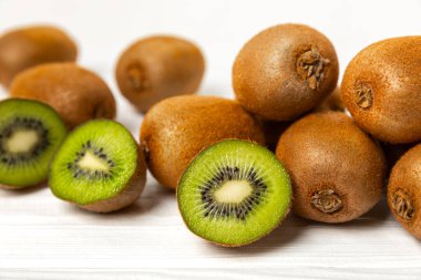 Ahşap arka planda Kivi. Masada tam meyve ve dilimler halinde yeşil kivi var. Taze sulu kivi. Tropik meyve. Organik meyve. Sağlıklı beslenme. Mesaj için yer var. Boşluğu kopyala