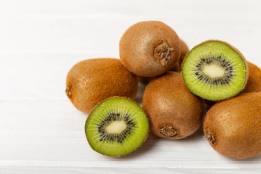 Ahşap arka planda Kivi. Masada tam meyve ve dilimler halinde yeşil kivi var. Taze sulu kivi. Tropik meyve. Organik meyve. Sağlıklı beslenme. Mesaj için yer var. Boşluğu kopyala