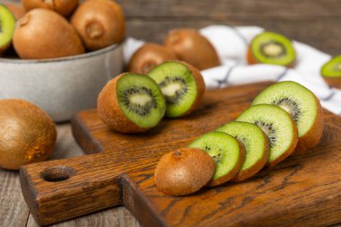 Ahşap arka planda Kivi. Masada tam meyve ve dilimler halinde yeşil kivi var. Taze sulu kivi. Tropik meyve. Organik meyve. Sağlıklı beslenme. Mesaj için yer var. Boşluğu kopyala