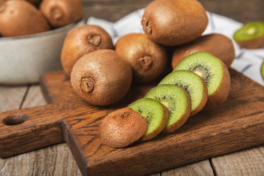 Ahşap arka planda Kivi. Masada tam meyve ve dilimler halinde yeşil kivi var. Taze sulu kivi. Tropik meyve. Organik meyve. Sağlıklı beslenme. Mesaj için yer var. Boşluğu kopyala
