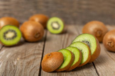 Ahşap arka planda Kivi. Masada tam meyve ve dilimler halinde yeşil kivi var. Taze sulu kivi. Tropik meyve. Organik meyve. Sağlıklı beslenme. Mesaj için yer var. Boşluğu kopyala